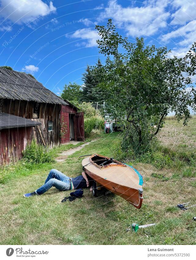 Man repairing Klepper folding boat Collapsible boat Summer Jeans Grass Nature Colour photo Meadow Human being Relaxation Sky Lie Landscape Blue Exterior shot