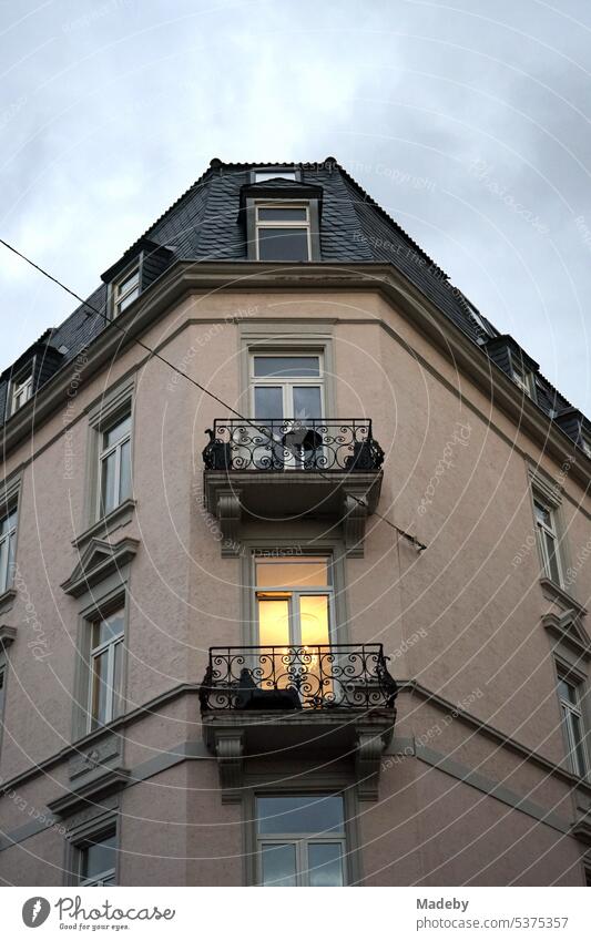 Light behind the window of an old corner house with beautiful balcony and light in the living room in the evening in the Bornheim district of Frankfurt am Main in Hesse, Germany