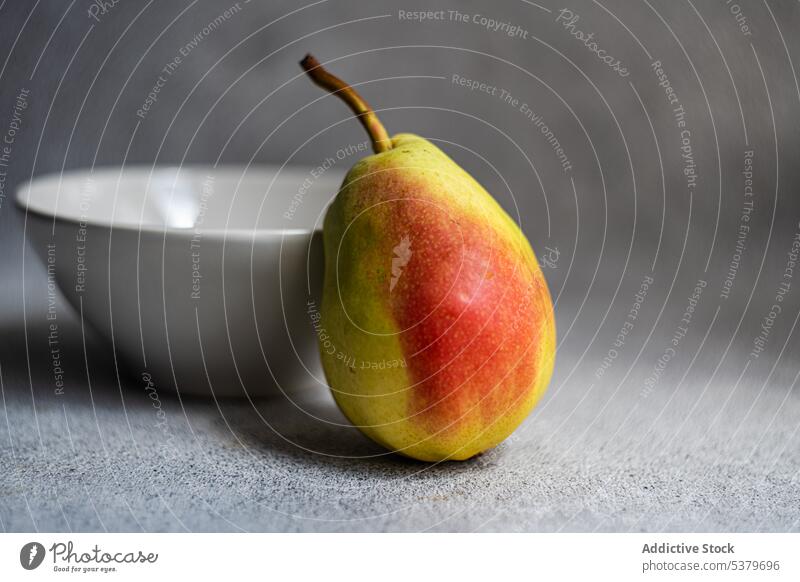 Healthy pear fruit near bowl on blurred background concrete diet gourmet healthy nutrition one only organic raw ripe seasonal stoneware summer superfood table