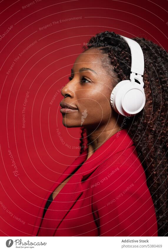 Thoughtful woman listening to music with headphones serious wireless style trendy melody positive black female african american song device modern meloman sound