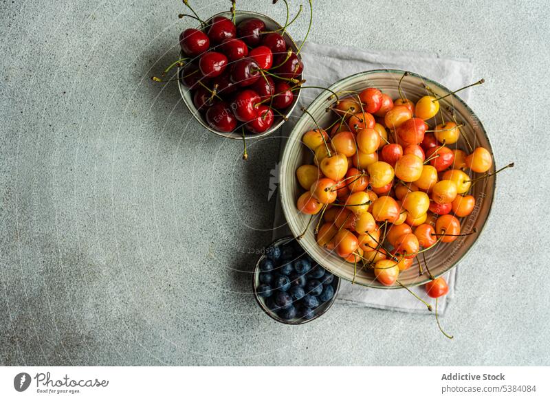 Sweet cherries in the bowl assortment background berry blue blueberry cherry concrete dessert eat eating food fresh fruit healthy meal napkin organic red ripe