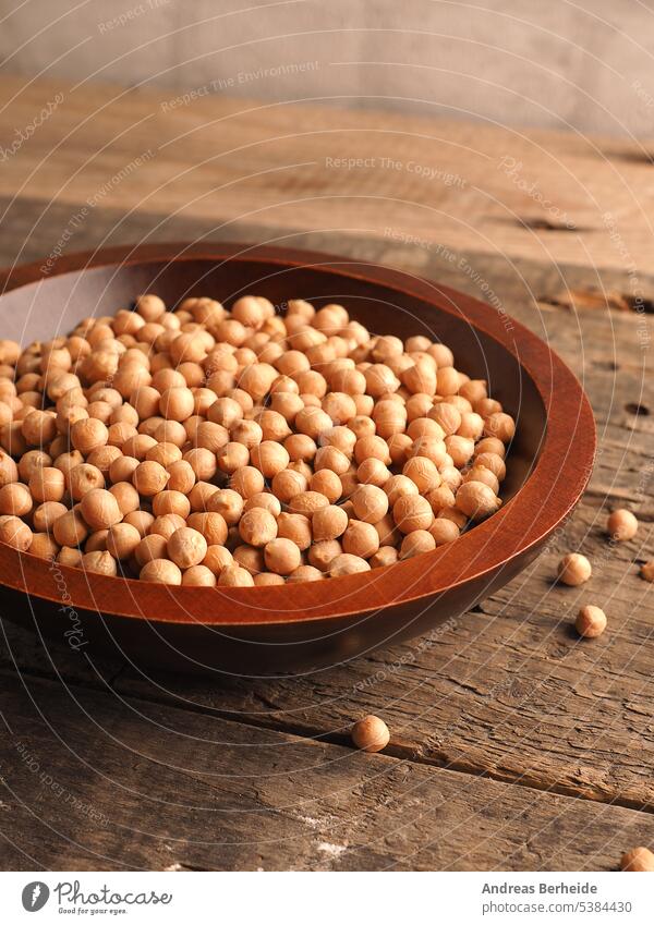 Organic dried chickpeas in a wooden bowl on a rustic wooden kitchen table organic portion harvest nourishment cereal grain pile protein uncooked vegetarian eat