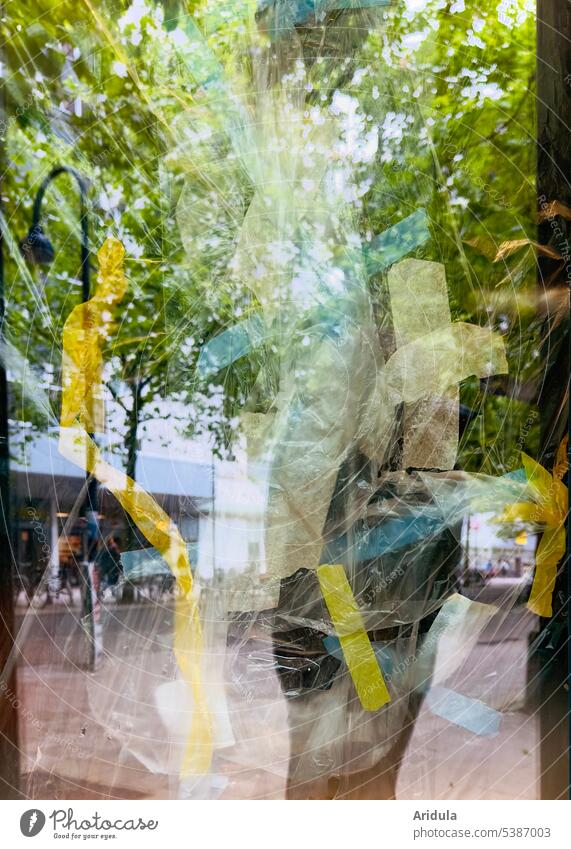 Pedestrian zone reflected in empty shop window covered with foils and adhesive strips from the inside Pedestrian precinct Town Shop window Packing film