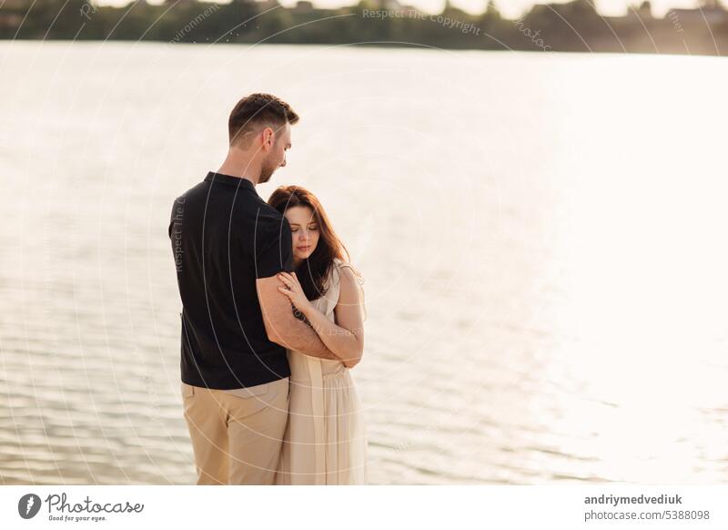 Romantic couple is hugging outdoors. elegant and stylish woman and man in love are walking along the lake. Happy moments together. love story beach water people