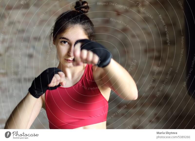 Young woman during a boxing training. Female boxer doing fitness. strong young fight gaze workout gym girl bag punching sport club purposeful hit female