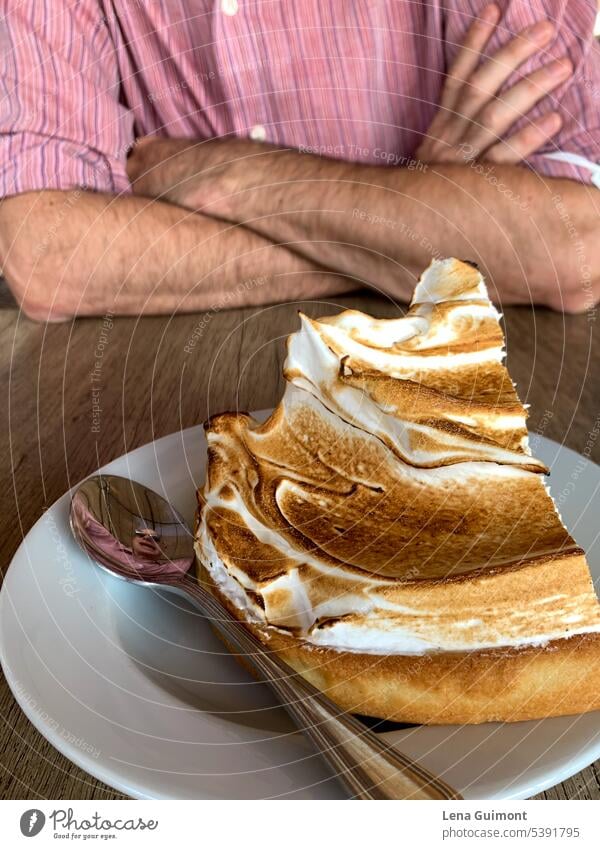 Man with crossed arms with cake Table pink Shirt Stripe Meringue pie Spoon Plate Porcelain Brown Exterior shot Gateau Dessert White Baked goods cute