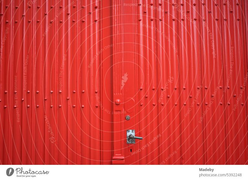 Beautiful old door of a garage or Einfahret in red with silver handle in the alleys of the old town of Bruges in West Flanders in Belgium quality
