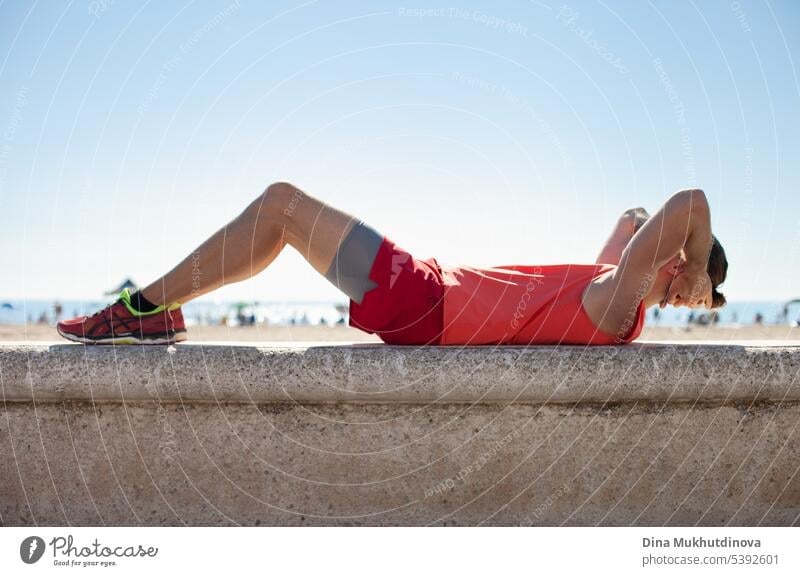 Unrecognizable person in red fitness outfit doing exercise on the beach on a sunny day. Outdoor workout. active activity adult athlete body caucasian city