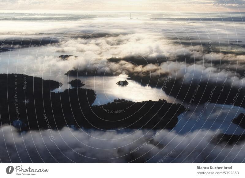 Aerial view from above clouds early morning over Trakai in Lithuania with water and small islands in sunlight. Exterior shot Colour photo Aerial photograph