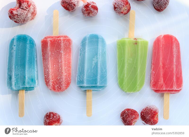Icy multicolored popsicles on a stick on a white background.  Fruit ice with frozen strawberries on a white background. Food summer cream cold refreshing mint