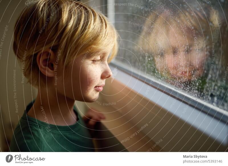 Portrait of preteen boy standing at the window. Child watching the rain outside. child candid hope love kind hearty safe-regulation skill empathy faith emotive