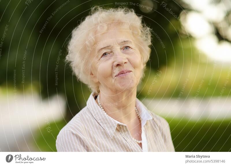 Outdoor portrait of beautiful senior woman with curly white hair lady healthy face elderly real lifestyle vitality positive pensioner grandmother beauty female
