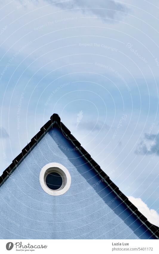 Sloping roof, round window in front of gray blue sky Day Manmade structures Facade Blue sky Bright Roof urban lines Town Building House (Residential Structure)