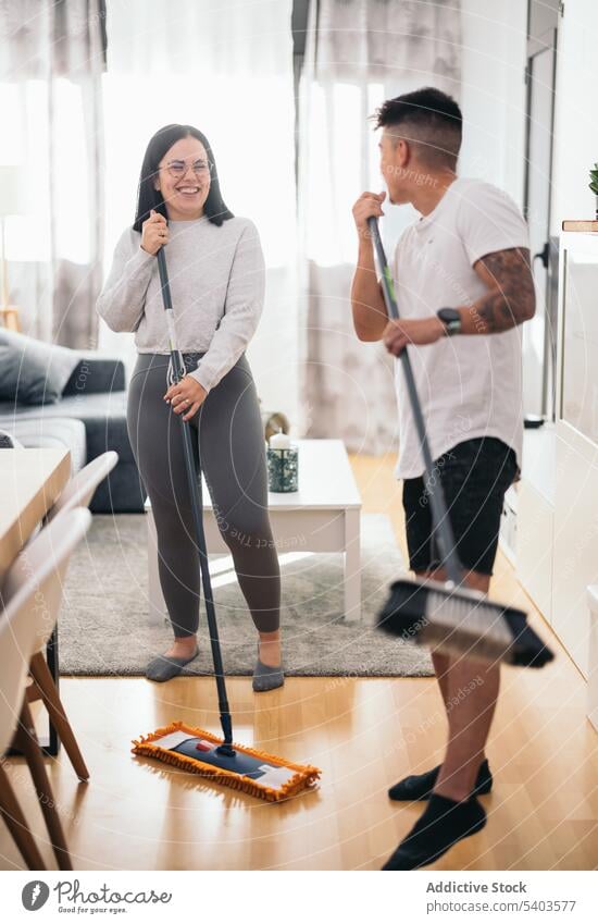 Young couple having fun while cleaning the house apartment caucasian clean up cleaner dancing dirty disinfection domestic female funny home household
