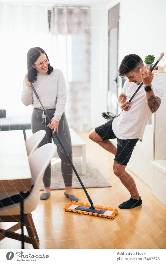 Young couple having fun while cleaning the house apartment caucasian clean up cleaner dancing dirty disinfection domestic female funny home household