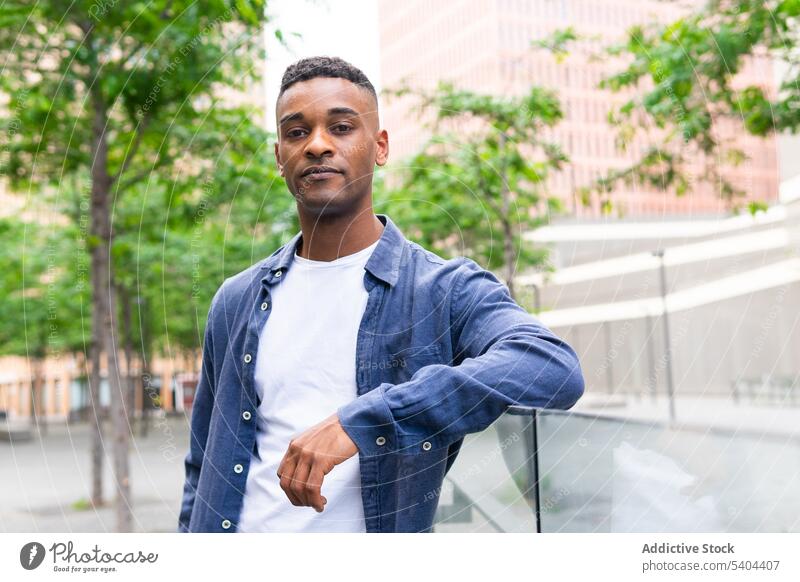 Black man relaxing on day off cityscape park green tree chill self confident portrait male black african american rest weekend leisure pastime recreation street