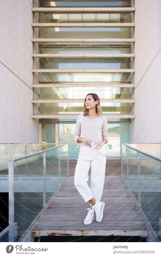 Middle aged woman near an office building carrying an eco-friendly ecological metal water bottle. middle aged thermos stainless fashionable environment friendly