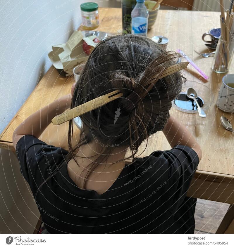 Boy with long hair wears chignon with bamboo wood hairpin at breakfast table Breakfast Table long hairs Boy (child) Brunette Hair up Chignon Bamboo wood Eating