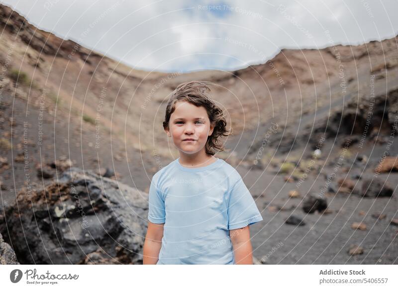 Pensive kid standing on rocky formation in mountainous area child serious stone boulder enjoy blue sky pensive summer girl highland childhood preteen admire