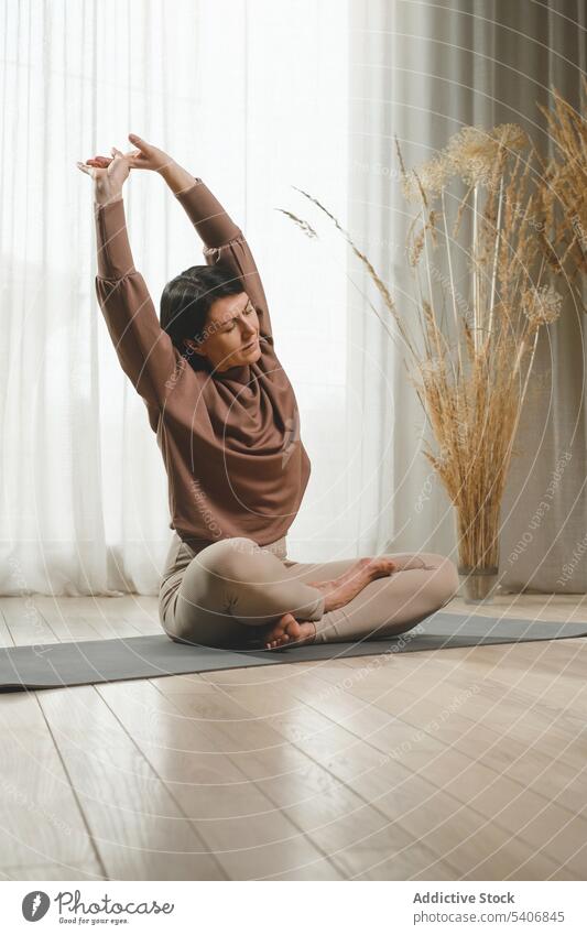 Calm woman stretching on mat near curtain at home meditate yoga zen practice calm female barefoot sportswear stress relief wellness mindfulness eyes closed