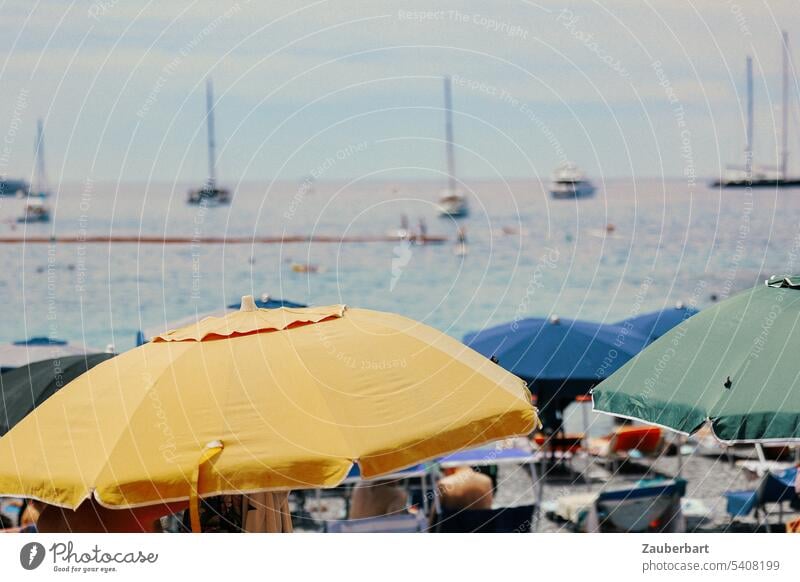 Parasols in yellow, blue and green, the sea behind, on the coast of the Italian Riviera Sunshade Yellow Blue Liguria Green stand Ocean Water boats bathe