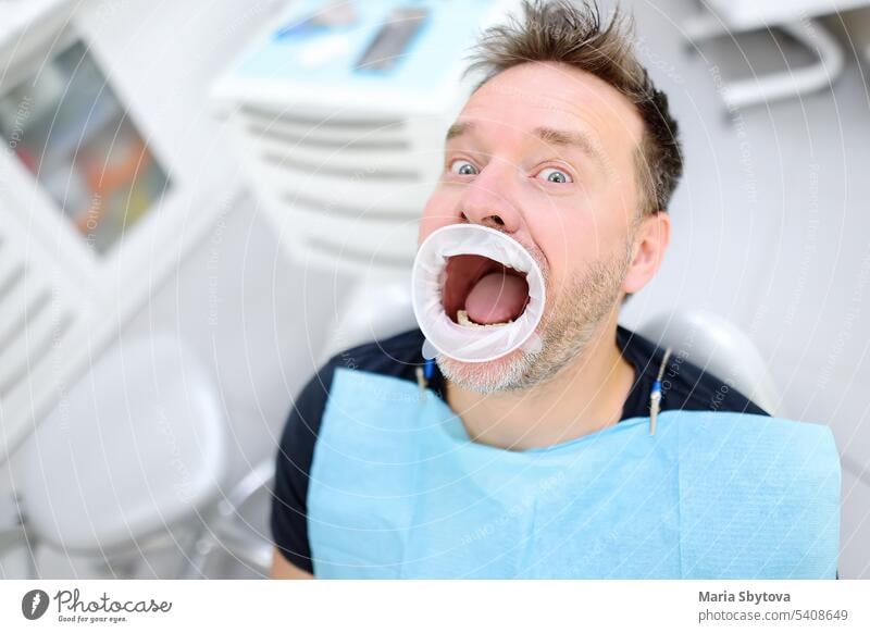 Frightened patient in the chair on dental clinic. Orthodontist and prosthetics appointment. Fear of dentists concept. treat teeth fear fright cavity funny mouth
