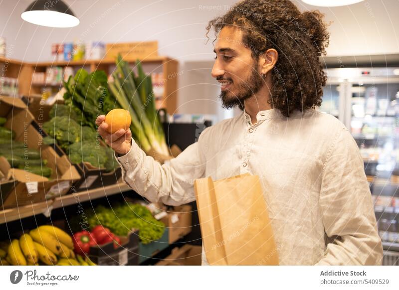 Happy man choosing fruit in shop by vegetable shelf paper bag grocery customer supermarket buyer portrait store goods male young shopper happy retail casual