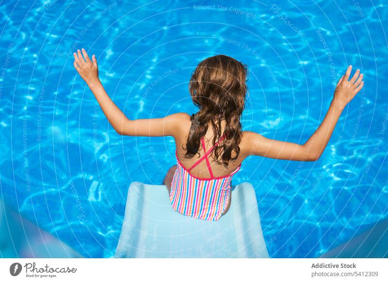 Back view of girl with raised hands by tip of slide in swimming pool - a  Royalty Free Stock Photo from Photocase