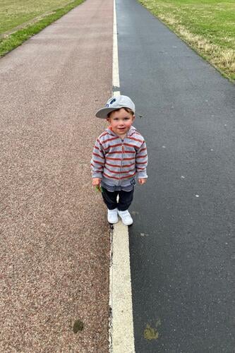 Child on sidewalk off Line Asphalt Cap 2 years Red White Black Street Exterior shot Signs and labeling Colour photo Transport Gray Stripe decide Decide Jacket