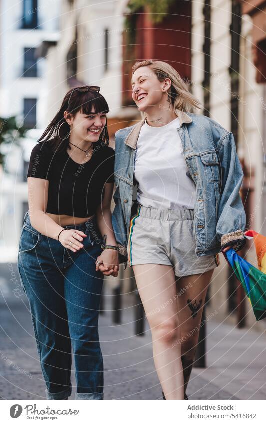 Lesbian couple with LGBT flag walking on street lesbian lgbt happy waving city young together women casual homosexual pride equality alternative relationship