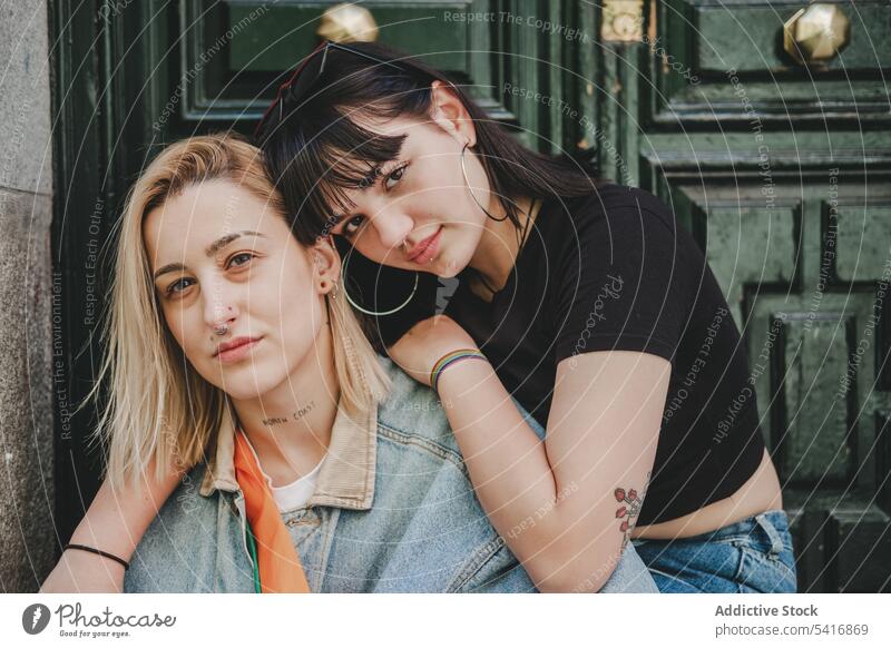 Lesbian couple sitting near door lesbian embracing women love street city building young casual hugging tender homosexual lgbt alternative together feelings