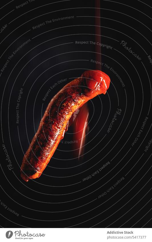 ketchup falling on grilled sausage in a black background clipping path meal gastronomy unhealthy close-up roasted meat prepared ingredient fried restaurant