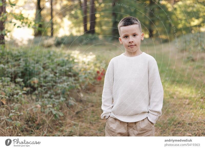 Portrait of little child boy is smiling and looking in camera in the park background. Kid, parenting, happy and joyful emotions, carefree, funny face, discover new world. Concept of a happy childhood