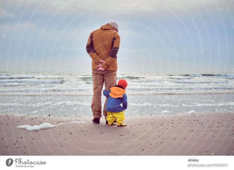 Toddler carefully watches the waves from behind his father Discover Autumn safeguarded monitoring cautious Waves stormy Study Denmark vacation Infancy Family