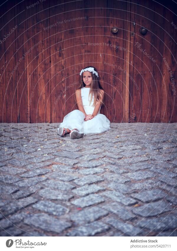 Little girl sitting near huge wooden door rest child relax beautiful little adorable kid cute female innocence pensive purity individuality comely sweet hair
