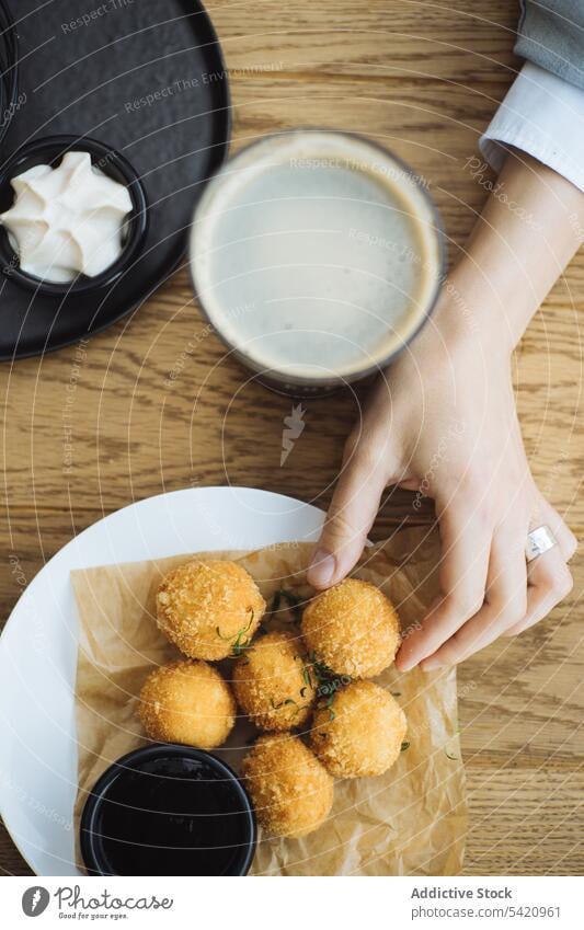 Woman eating potato croquette at table ball fried hand food crunch junk delicious snack tasty plate meal cuisine dish tradition nutrition serve yummy person