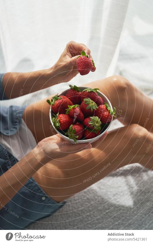 Crop woman with strawberries sitting on bed strawberry bowl home show summer weekend ripe female rest food fruit dessert morning blanket bedroom organic comfort