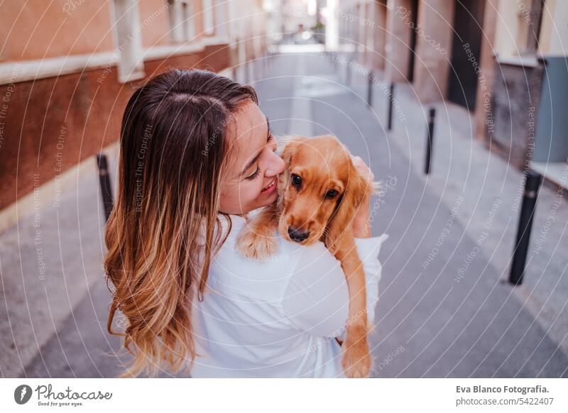 young woman at the street holding with her cute cocker dog on shoulder. Lifestyle outdoors with pets walking city urban purebred caucasian coker lifestyle