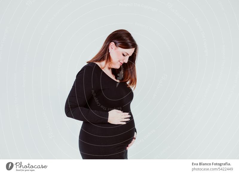 young pregnant woman of 21 weeks at home touching her belly and smiling.  family concept - a Royalty Free Stock Photo from Photocase