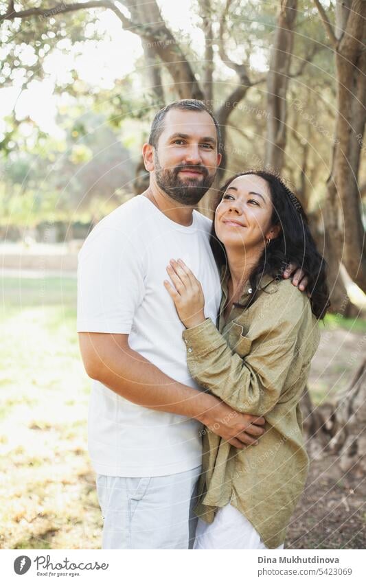 couple hugging in summer park looking to the camera  in olive grove in green olive color palette. Earthy tones love and couple goals aesthetic. family together