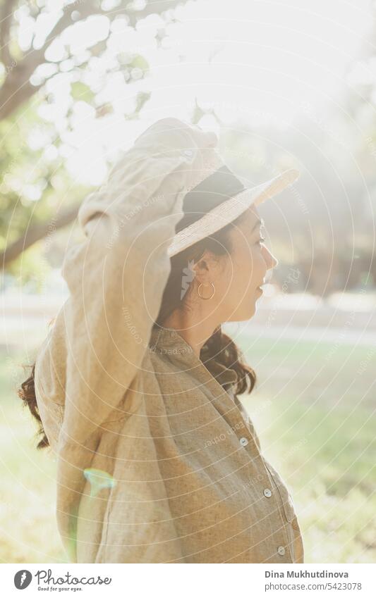 beautiful 30 year old millennial woman looking back in hat and olive green linen shirt in the park with soft sunlight autumn or summer portrait Woman