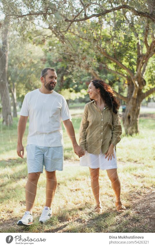 couple hugging in summer park in olive grove in green olive color palette. Earthy tones love and couple goals aesthetic. family together Olive grove linen