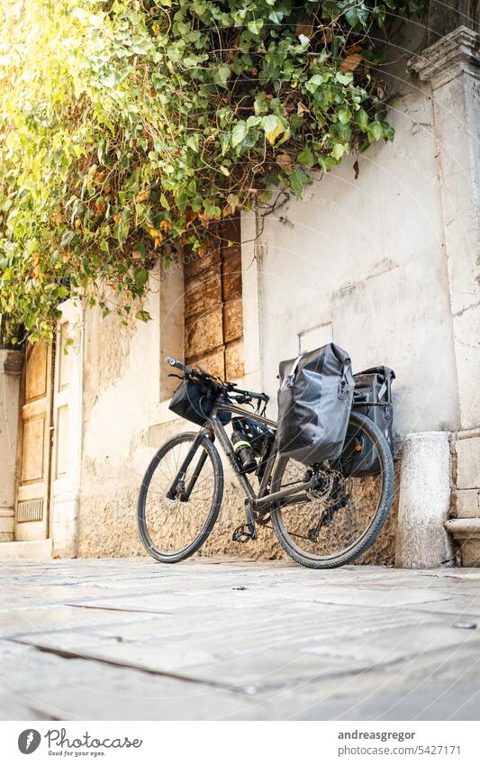 Bicycle with loaded bags leaning against a house wall in an alley in a southern European town Bicycle tour Cycling tour bike packing vacation Southern European
