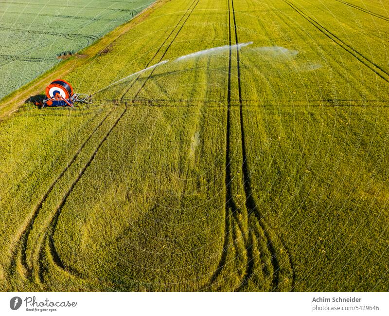 Water pump with trolley and sprinkler for irrigating a field as aerial view water pump cart irrigation sprinkler system grain summer sprayed germany