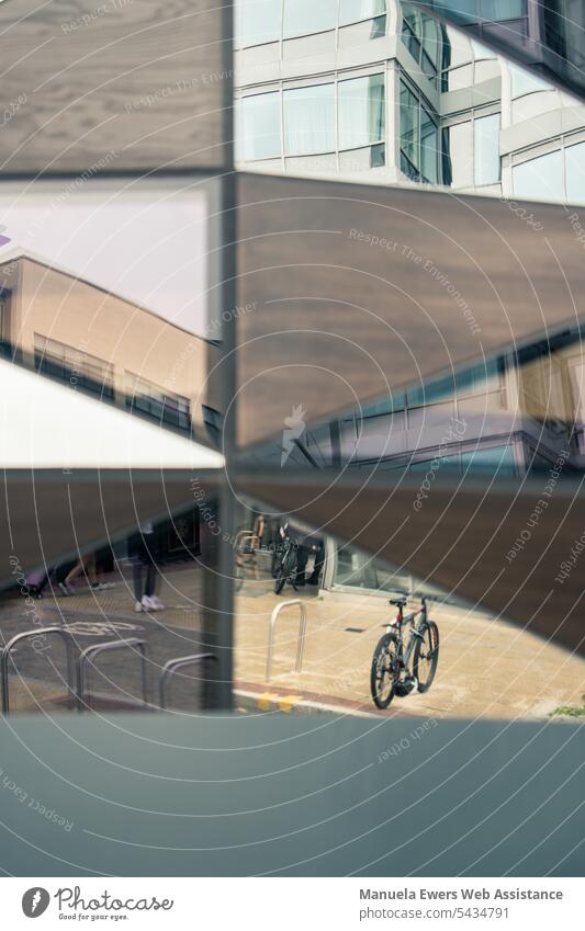 The facade of a building reflects bicycles, street and building Abstract reflection Bicycle Transport Building Divided nested disassociated Contrast Street