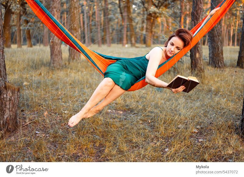 Young Hispanic woman reading a book in hammock in the woods person cat holiday enjoy paradise relax relaxation lying female young leisure lifestyle nature