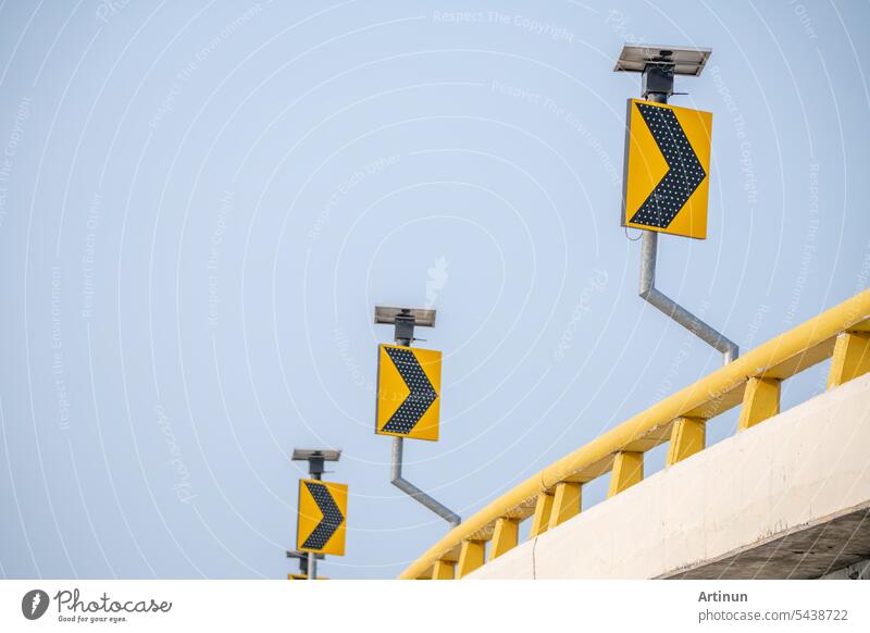 Yellow traffic signs guide drivers along curve roads. Symbols ensure safety as they navigate the streets under the watchful blue sky. Arrow sign on signpost of highway against blue sky.