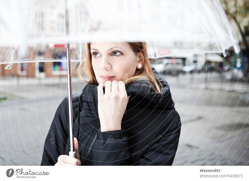 Young woman holding transparent umbrella caucasian european caucasian ethnicity caucasian appearance looking sideways sideways glance outdoors location shot