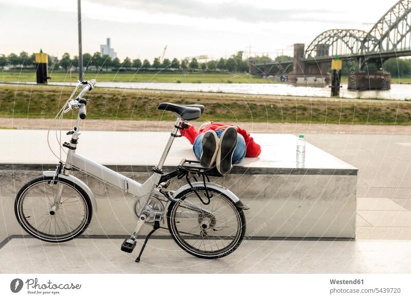 Senior woman with city bike having a break lying on platform females women bicycle bikes bicycles Adults grown-ups grownups adult people persons human being