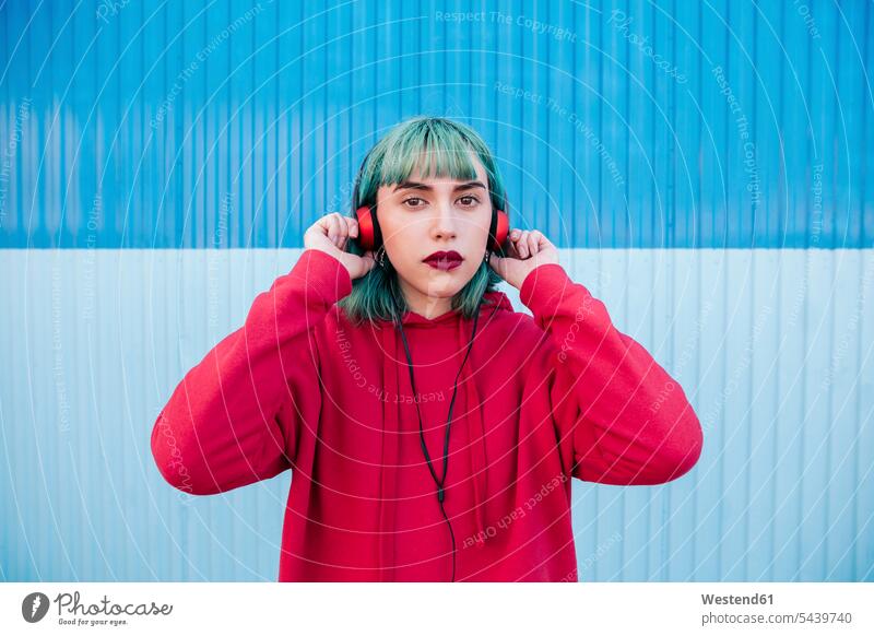 Portrait of young woman with blue dyed hair listening music with headphones headset females women portrait portraits coloured hearing Adults grown-ups grownups